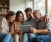 Famille multigenerations souriante avec tablette dans un salon lumineux